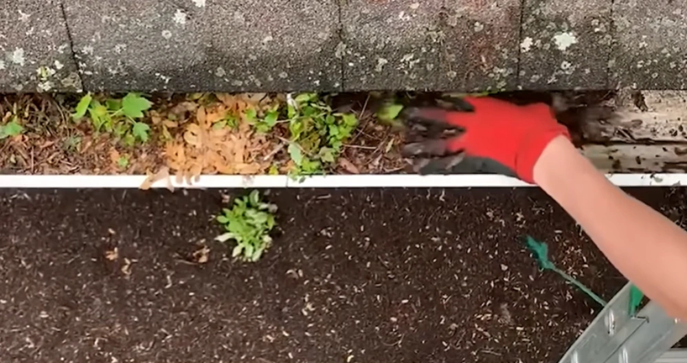 Clearing gutter debris by hand before the storms