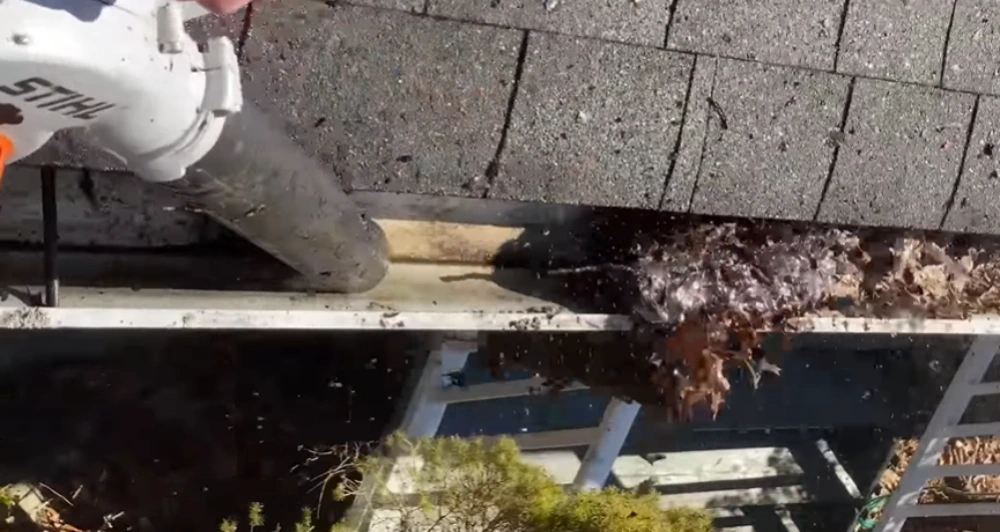 Clearing leaves from gutter blower