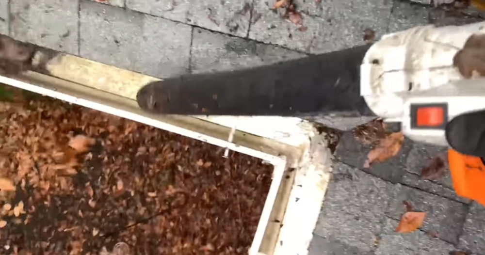 Clearing leaves from a gutter before the rains