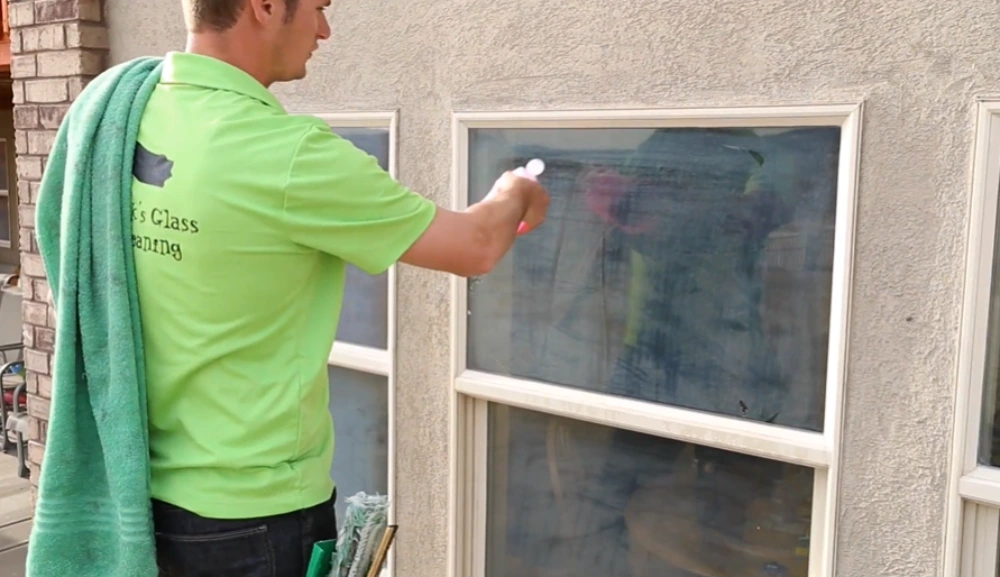 Spraying cleaner on window glass