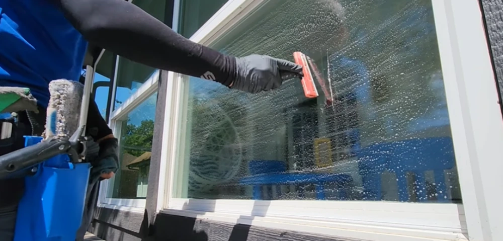 Squeegee on soapy window glass close-up