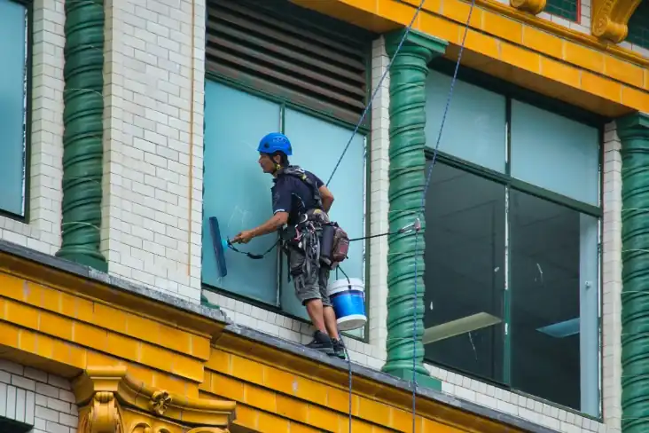 Window cleaner on rope access cleaning a commercial building